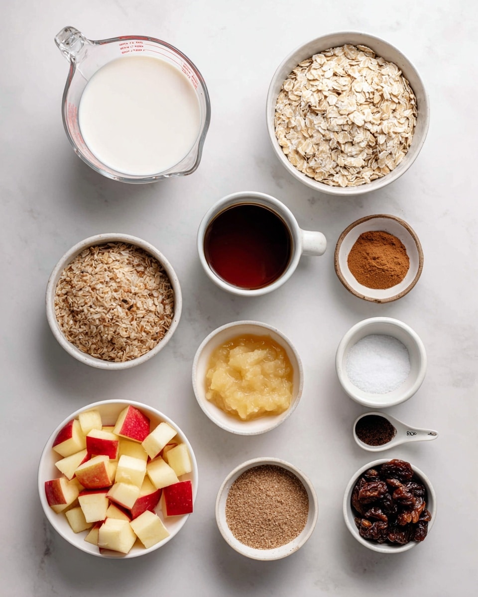 The image shows various ingredients for a recipe arranged neatly on a white marbled surface. At the top left is a clear glass measuring cup filled with white non-dairy milk. To its right is a white bowl filled with light tan rolled oats. Below the measuring cup is a white cup containing dark brown maple syrup. Next to it, a small white bowl holds light brown ground flaxseed. To the right, a small white bowl has a mix of brown cinnamon powder, white baking powder, and white sea salt. Below those, there is a clear bowl with light yellow unsweetened applesauce, and next to it a small white bowl with white coconut oil. Near the bottom left corner, a white bowl contains diced apples with red and yellow skin. To the right is a white bowl filled with dark brown raisins, and above it a small white cup holds dark vanilla extract. All items are spaced evenly and labeled clearly. Photo taken with an iphone --ar 4:5 --v 7