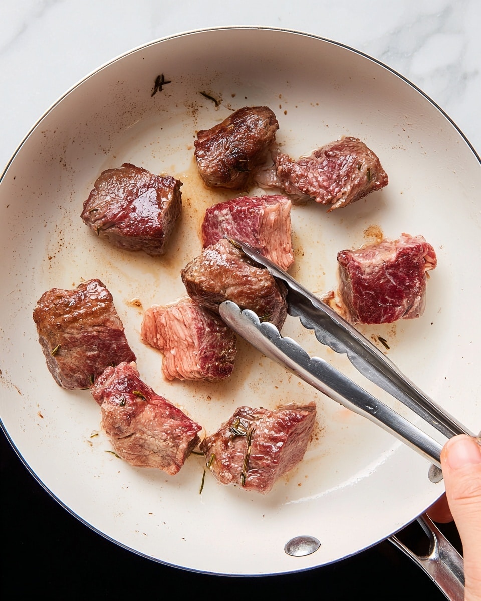 A white pan with seven pieces of meat inside, some browned and some still raw with red and pink colors, one piece held by silver tongs gripped by a woman's hand on the lower right; the pan's surface shows light browning marks from cooking, all set against a white marbled background photo taken with an iphone --ar 4:5 --v 7