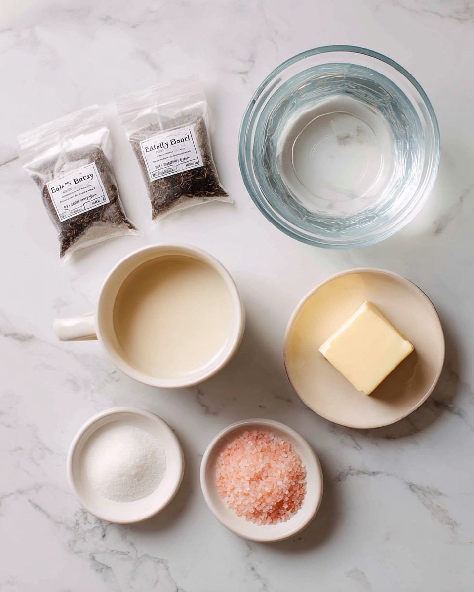 The image shows several ingredients arranged on a white marbled surface. At the top right, there is a clear glass bowl filled with water. To the left of the bowl, there are two tea bags labeled Earl Grey Black Tea. Below the bowl, a white cup contains a creamy white liquid identified as half and half. Next to the cup on the right, a small white bowl holds a square piece of butter. Below the butter, another small white bowl contains pink Himalayan salt powder. Each ingredient is labeled with simple text boxes in light pink, placed near the items. The setting is bright and clean, with a top-down view photo taken with an iphone --ar 4:5 --v 7
