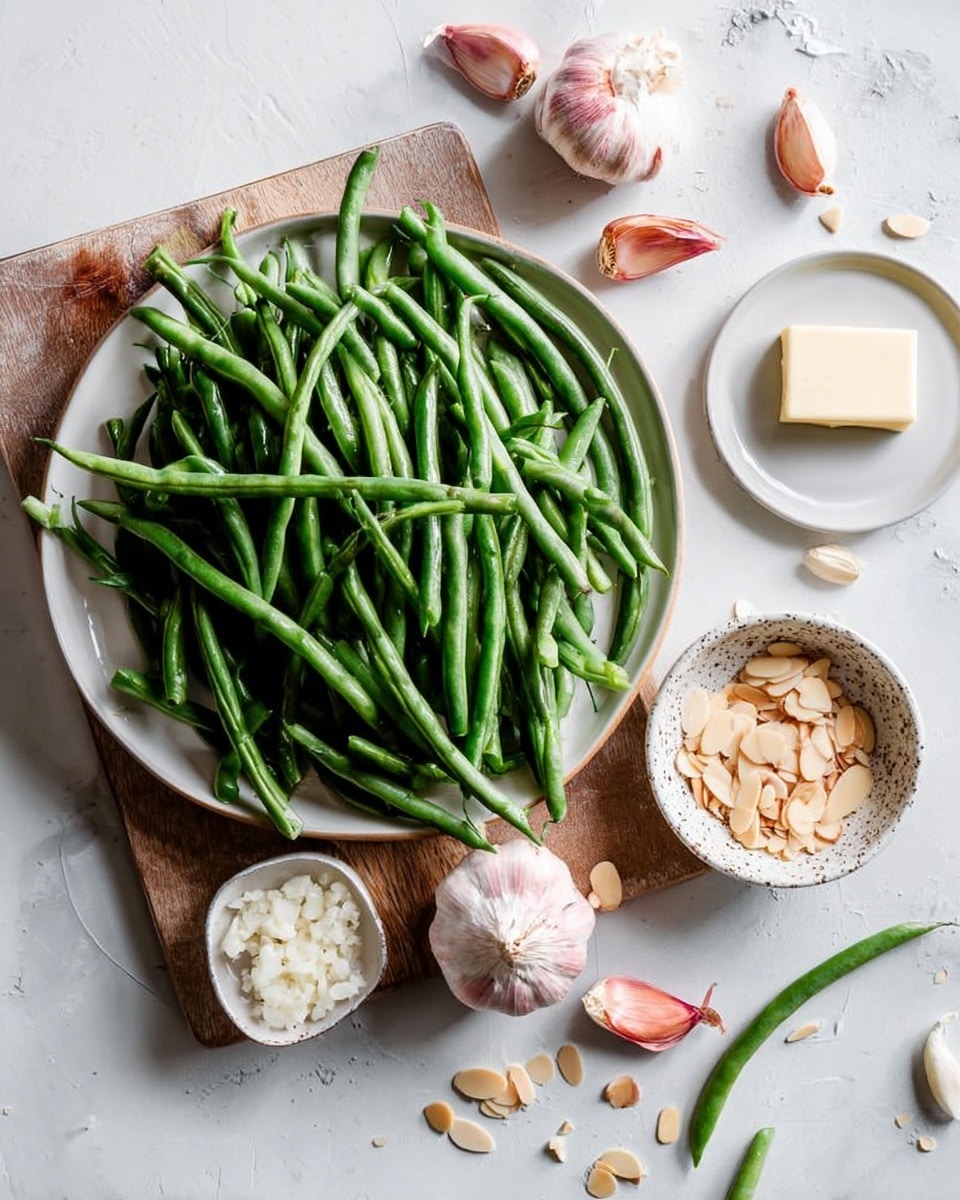 A large white plate with green beans piled high over a wooden board, surrounded by two whole garlic bulbs, two small pink shallots, a small white bowl filled with chopped shallots, and a speckled bowl holding sliced almonds. A small white plate with a square piece of butter is placed nearby. The background is a white marbled surface that creates a clean, fresh look. Some green beans and almond slices are scattered casually around the setup, giving a natural and fresh feeling. Photo taken with an iphone --ar 4:5 --v 7