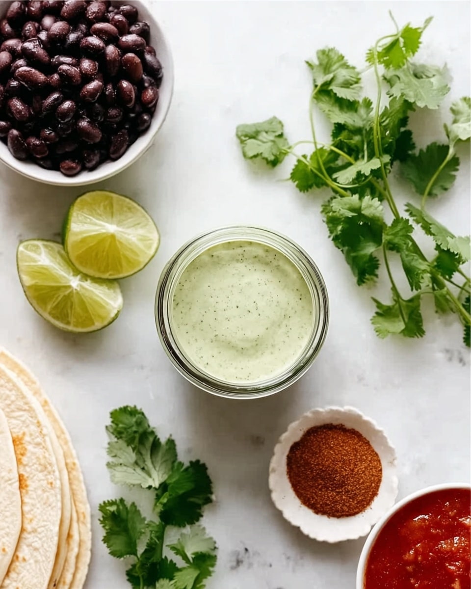 The image shows a top-down view of a small glass jar filled with light green sauce, placed near a small white bowl with black beans. Around the jar, there are fresh cilantro leaves spread out on a white marbled surface, two lime wedges near the jar, and a small white bowl containing red salsa on the right side. In the bottom left corner, part of a stack of white tortillas is visible, along with a small white dish filled with brown spice powder in the center of the image. The colors are fresh and natural, with the ingredients neatly arranged. Photo taken with an iphone --ar 4:5 --v 7