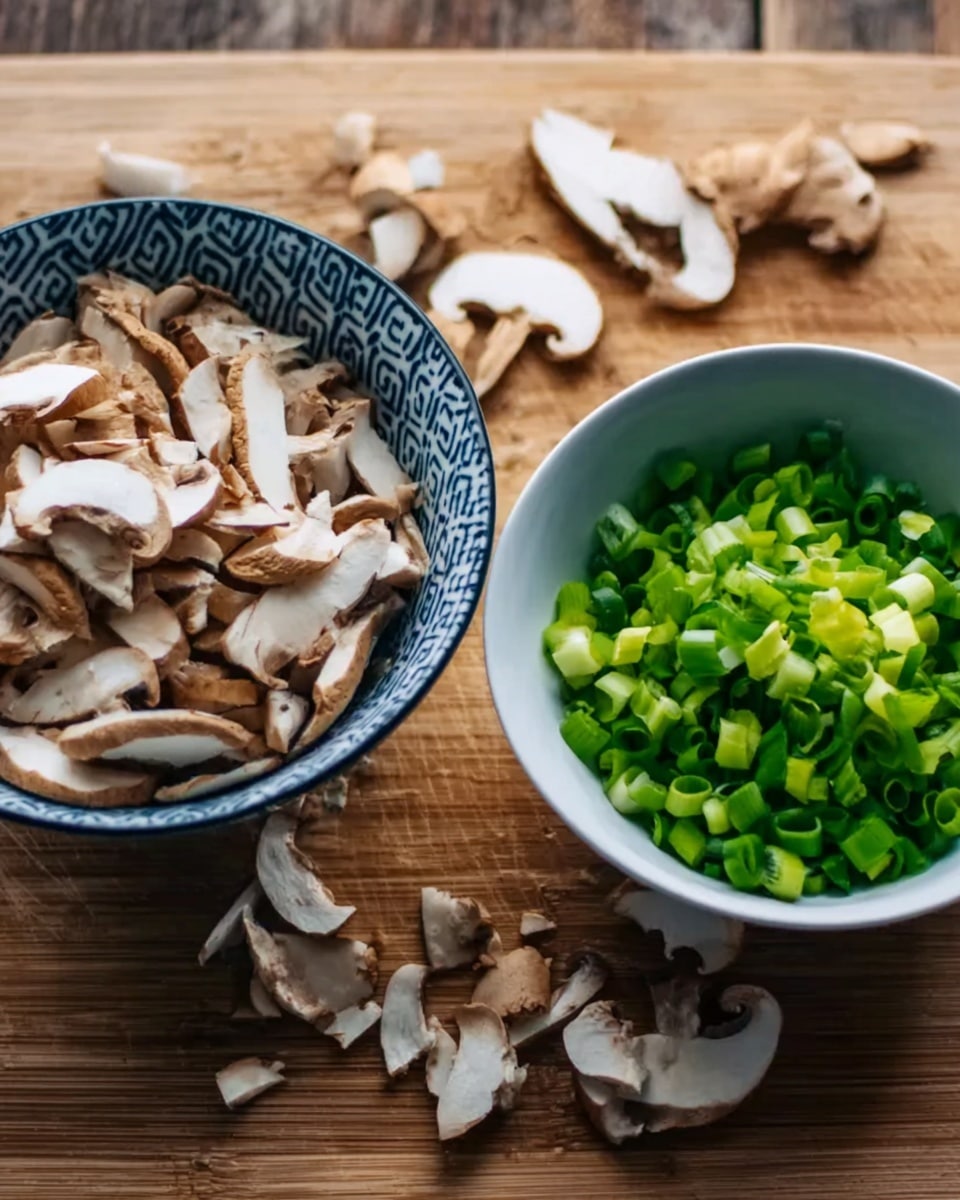The image shows two bowls on a wooden surface. The bowl on the left is white with a blue pattern and filled with sliced mushrooms that are light brown and white with a soft texture. The bowl on the right is plain white and holds bright green chopped scallions, with a fresh, crisp look. Some small pieces of mushrooms and scallions are scattered on the wooden surface around the bowls. photo taken with an iphone --ar 4:5 --v 7