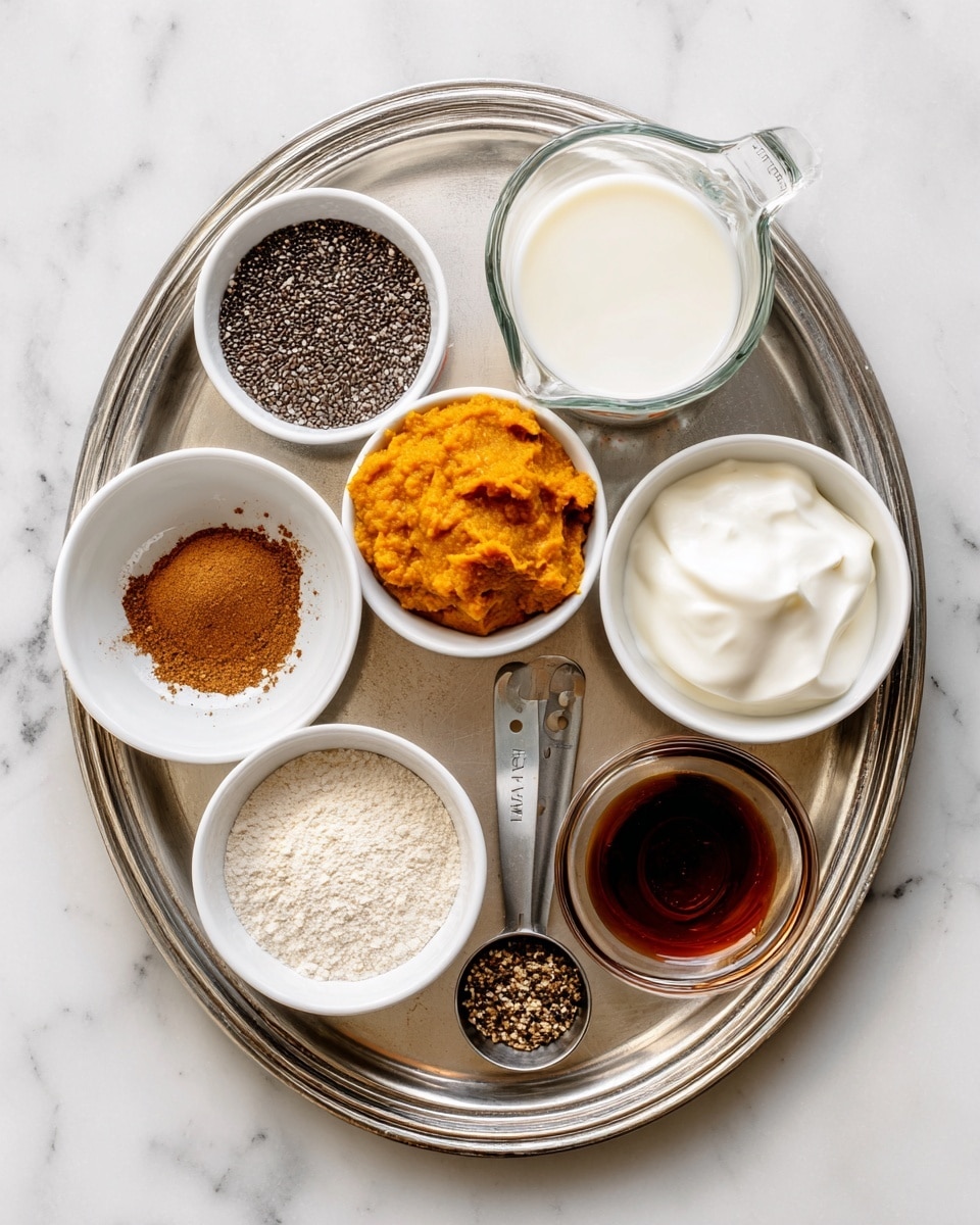 A silver tray holds eight white bowls and a clear measuring cup, each filled with different ingredients. Starting from the top left, there is a bowl filled with small, dark chia seeds, next to it on the right is a clear measuring cup filled with white milk. Below the chia seeds, a small bowl contains brown pumpkin spice and salt powder, and directly below that is a bowl filled with bright orange pumpkin puree. To the right of the pumpkin spice bowl is a bowl with smooth, white Greek yogurt, and below the yogurt is a small bowl with dark amber vanilla liquid. To the bottom right corner sits another bowl with a similar dark amber syrup, labeled maple syrup. On the bottom left corner is a bowl filled with off-white protein powder with a scoop taken out. The tray rests on a white marbled surface. photo taken with an iphone --ar 4:5 --v 7