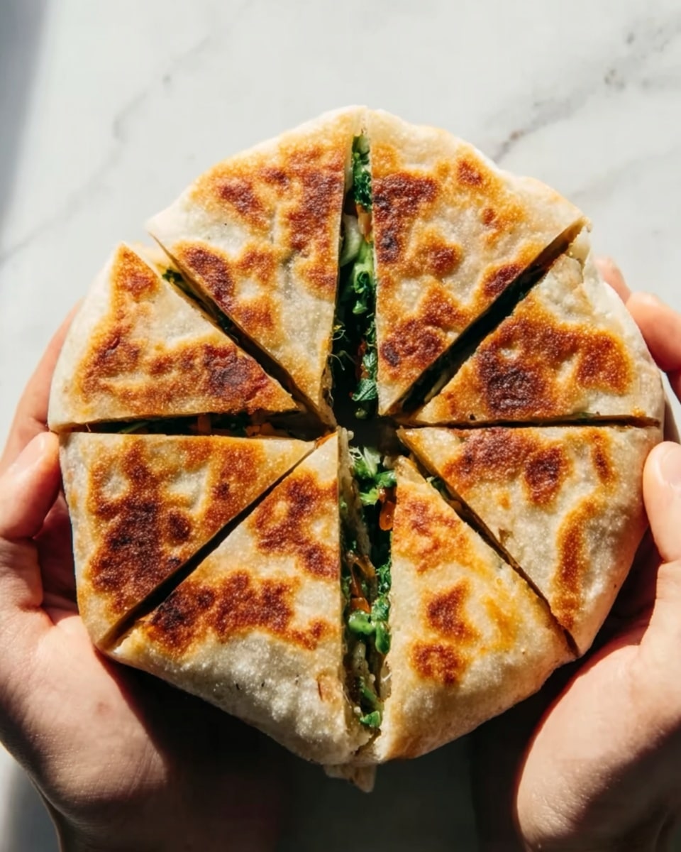 A round, golden-brown flatbread with visible crispy, toasted patches is held by two woman's hands against a white marbled background. The flatbread is cut into eight triangular pieces that come together to form a circle, with a dark green filling peeking through a vertical cut in the center. The texture of the bread looks soft inside with a crunchy outer layer, and the filling appears fresh and leafy, likely some kind of greens. The lighting is natural, highlighting the warm tones and crispy texture of the flatbread. photo taken with an iphone --ar 4:5 --v 7