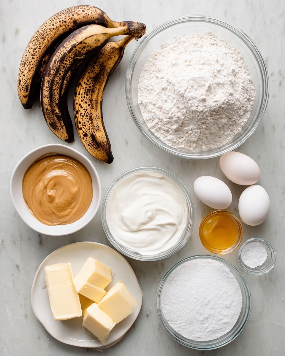 The image shows a collection of baking ingredients neatly placed on a white marbled surface. There are three dark brown ripe bananas with black spots at the top left. Next to them, a large clear bowl filled with white flour stands near another clear bowl full of thick, white yogurt or whipped cream. A smaller white bowl contains smooth light brown peanut butter, while another small clear bowl holds white granulated sugar. Two white eggs sit near a small white bowl with two pats of pale yellow butter. Below, a small white bowl has melted golden yellow butter, and a medium white plate is filled with powdered sugar. A few more small clear and white bowls with salt and baking powder complete the array of ingredients. Photo taken with an iphone --ar 4:5 --v 7