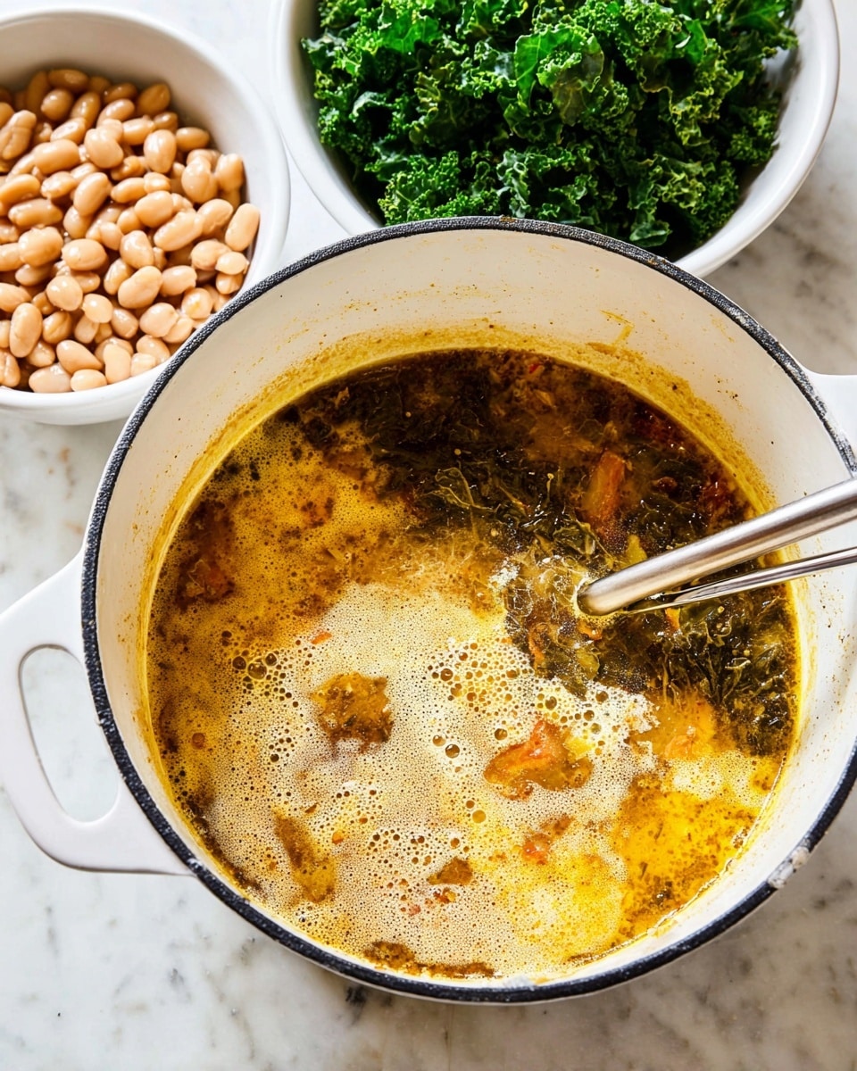 A round white pot with a black rim holds a soup being stirred by a metal stick, showing three main layers: a frothy cream-colored foam layer on top, beneath it an uneven mix of golden yellow and brown broth with some orange bits, and dark greenish areas around the edges. Behind the pot are two white divided dishes, one filled with fresh, curly dark green kale and the other with smooth, light tan beans. All items sit on a white marbled surface photo taken with an iphone --ar 4:5 --v 7