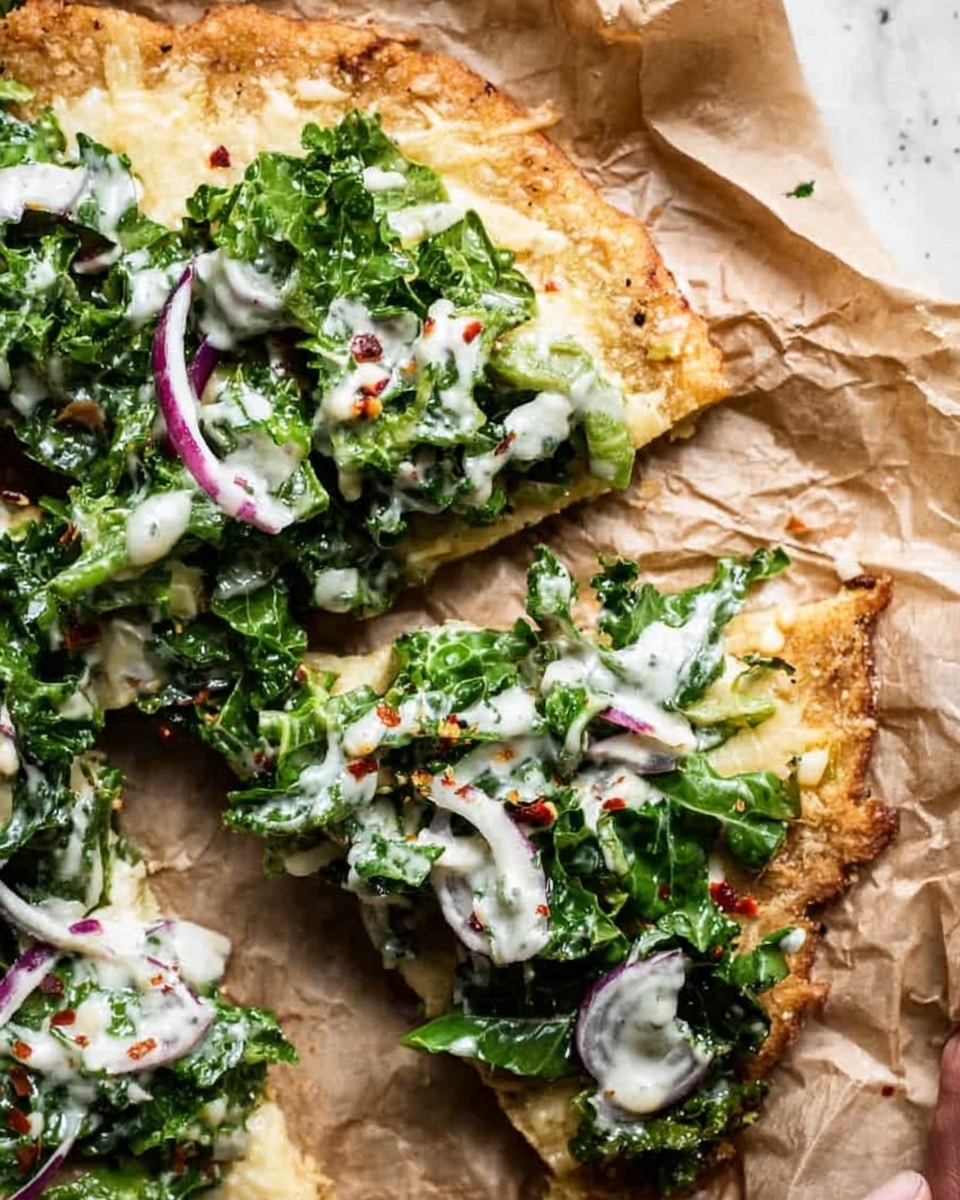 A close-up view of a flatbread pizza on crumpled brown parchment paper with a white marbled surface background, showing three visible layers: the bottom golden-brown crispy crust with a rough texture, a spread of melted pale yellow cheese covering the base, and a fresh green kale salad with creamy white dressing drizzled on top. Thin slices of purple onion are scattered over the salad, and small red chili flakes add a touch of color on the edges of the pizza. A woman's hand partially lifts one slice from the main piece, emphasizing the texture contrast between the layers. photo taken with an iphone --ar 4:5 --v 7