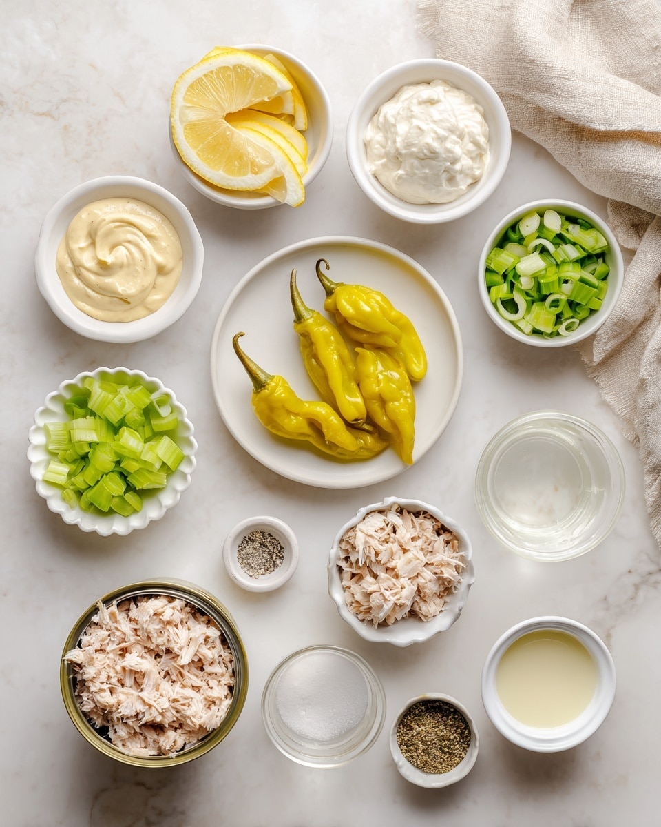 A white marbled surface holds an array of ingredients in small white bowls arranged neatly: bright yellow pepperoncini peppers sit in the center on a white plate; to the top left, a white bowl contains thin lemon wedges, and below it, a small white bowl with pale yellow dijon mustard. To the left bottom are creamy mayonnaise and bright green chopped celery in scalloped white dishes. In the middle, an open can of light pink canned tuna reveals shredded tuna pieces. Adjacent to it is a bowl of fresh green onion slices, a small white bowl of salt and pepper mix on the top right, and a bowl of thick white Greek yogurt. A small clear glass bowl of clear brine and a small cup of pale lemon juice complete the setup, all placed on a clean white marbled surface. A beige cloth peeks in from the top right corner. photo taken with an iphone --ar 4:5 --v 7