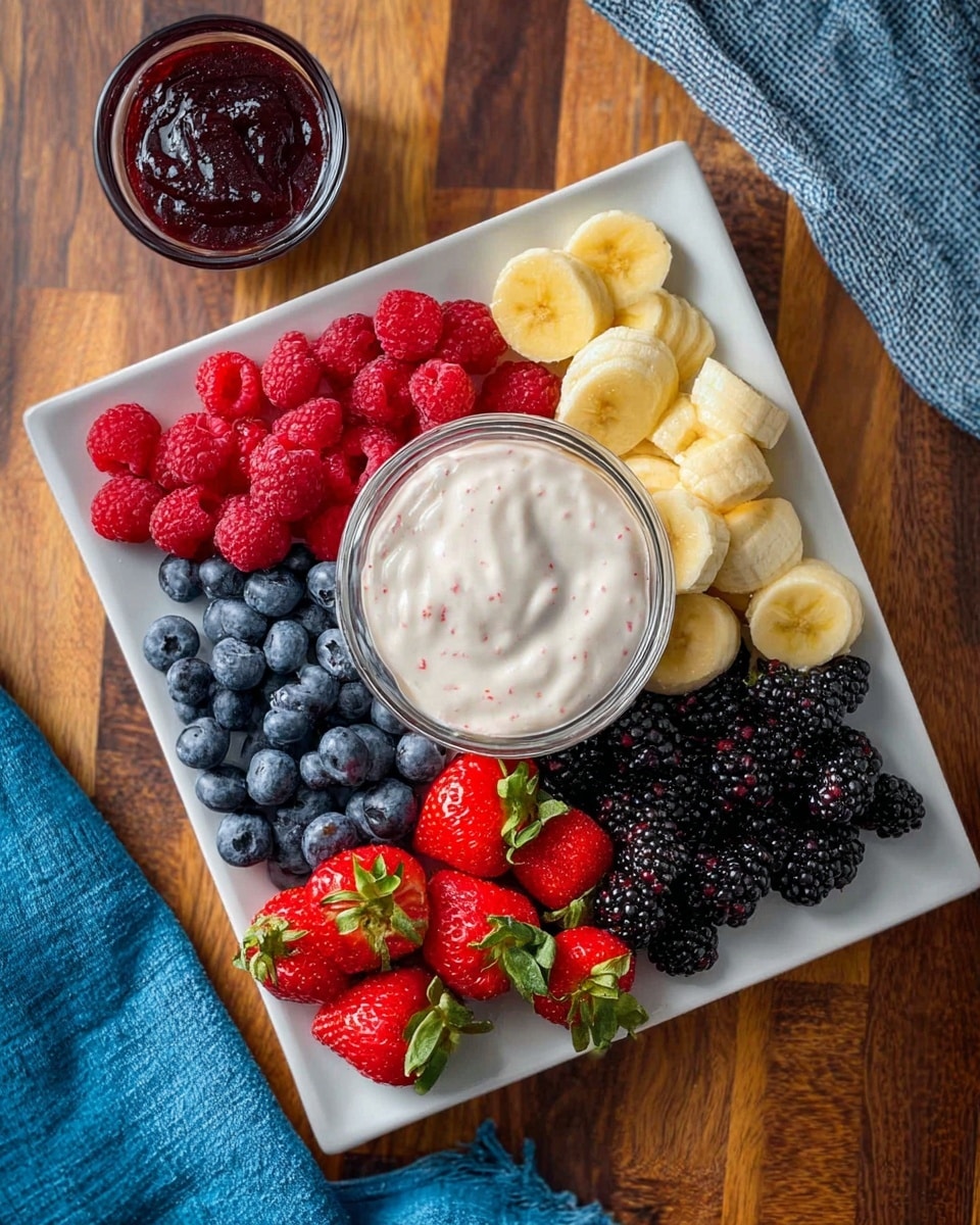 A white rectangular plate holds five sections of fresh fruit around a glass bowl filled with creamy white yogurt mixed with small red specks. Starting at the top left corner and moving clockwise, there is a pile of dark blue blueberries, bright red raspberries, sliced yellow bananas, shiny black blackberries, and whole red strawberries with green leaves. Next to the plate is a small clear glass bowl filled with dark red jam on a wooden chopping board background, and a blue cloth is partly visible on the upper right side. The photo taken with an iphone --ar 4:5 --v 7