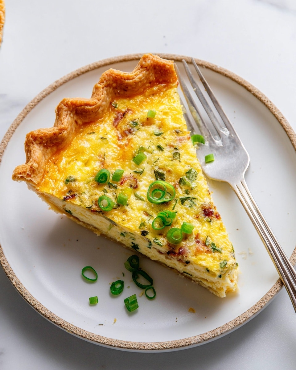 A single slice of quiche sits centered on a white plate with a rustic, golden-brown crust that is crimped at the edges, giving it a textured border. The quiche filling is yellow with a slightly fluffy, baked surface that shows bits of green herbs and small pieces of bacon inside. On top, several bright green, sliced scallions are scattered, adding color and freshness. A silver fork lies next to the slice on the plate, resting on the left side. The plate is set on a white marbled surface, creating a clean and bright background. photo taken with an iphone --ar 4:5 --v 7