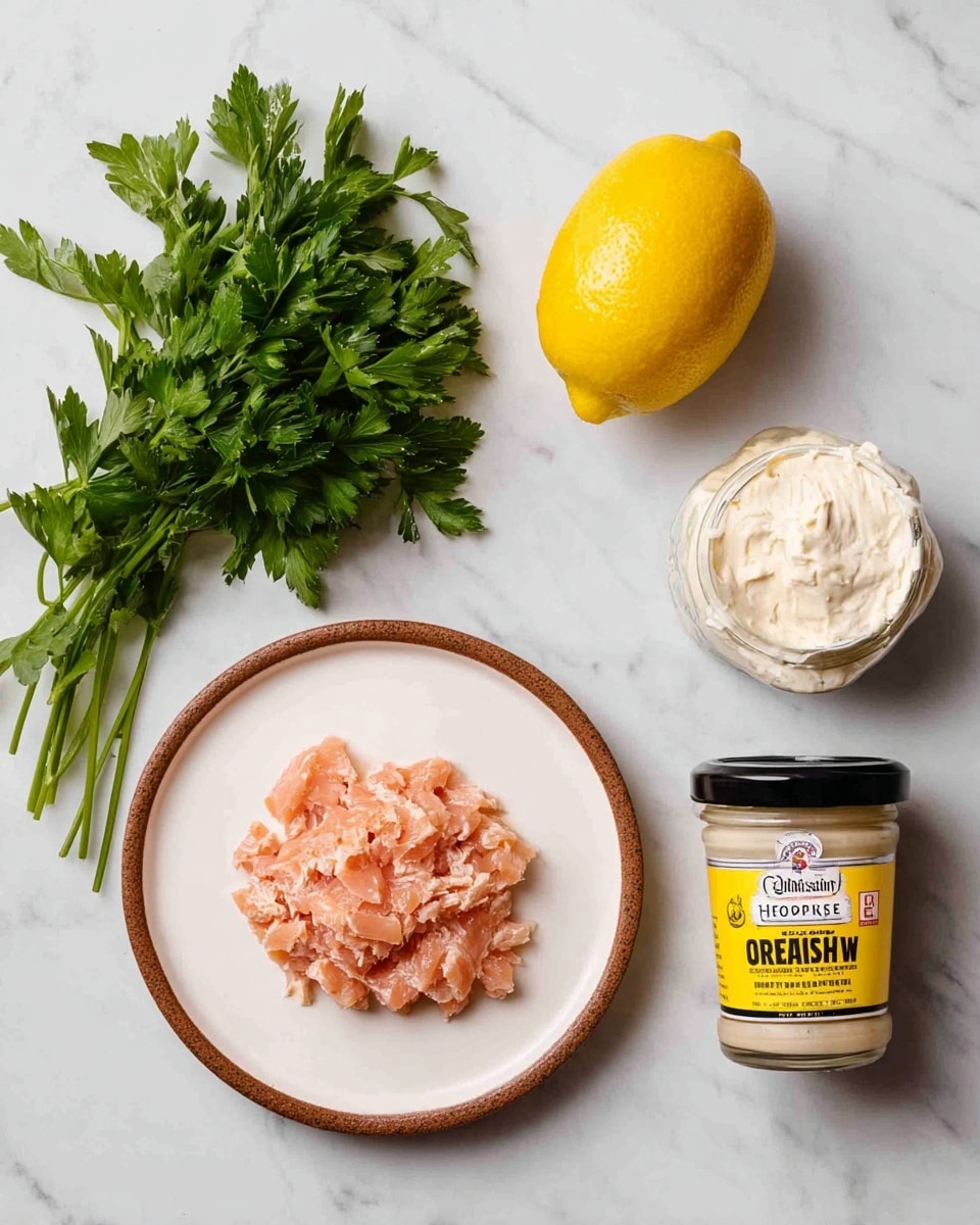 The image shows ingredients for a dish placed on a white marbled surface with fresh green parsley on the top left, a yellow lemon in the center right, a jar of horseradish sauce with a black lid and yellow label on the top right, and a white container of Philadelphia cream cheese underneath the lemon. On the bottom left, there is a white plate with a brown rim, holding a layer of finely broken pink smoked salmon spread in small pieces. The overall look is clean and simple with fresh and creamy elements. photo taken with an iphone --ar 4:5 --v 7