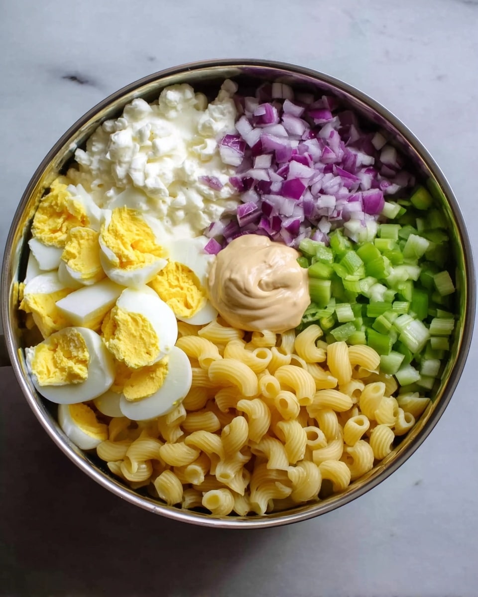 A large round metal bowl holds five different ingredients clearly separated in sections. On the top left is a white creamy layer with smooth texture. To the right of that is a layer of small chopped light green celery pieces. Next to the celery is a big section of pale yellow elbow macaroni pasta. Below the macaroni is a mound of hard boiled egg pieces showing bright yellow yolks mixed with white parts. To the left of the eggs is a layer of small chopped purple-red onions. In the center, over the eggs and macaroni, is a dollop of light tan mayonnaise creamy sauce. The bowl is placed on a white marbled surface. photo taken with an iphone --ar 4:5 --v 7