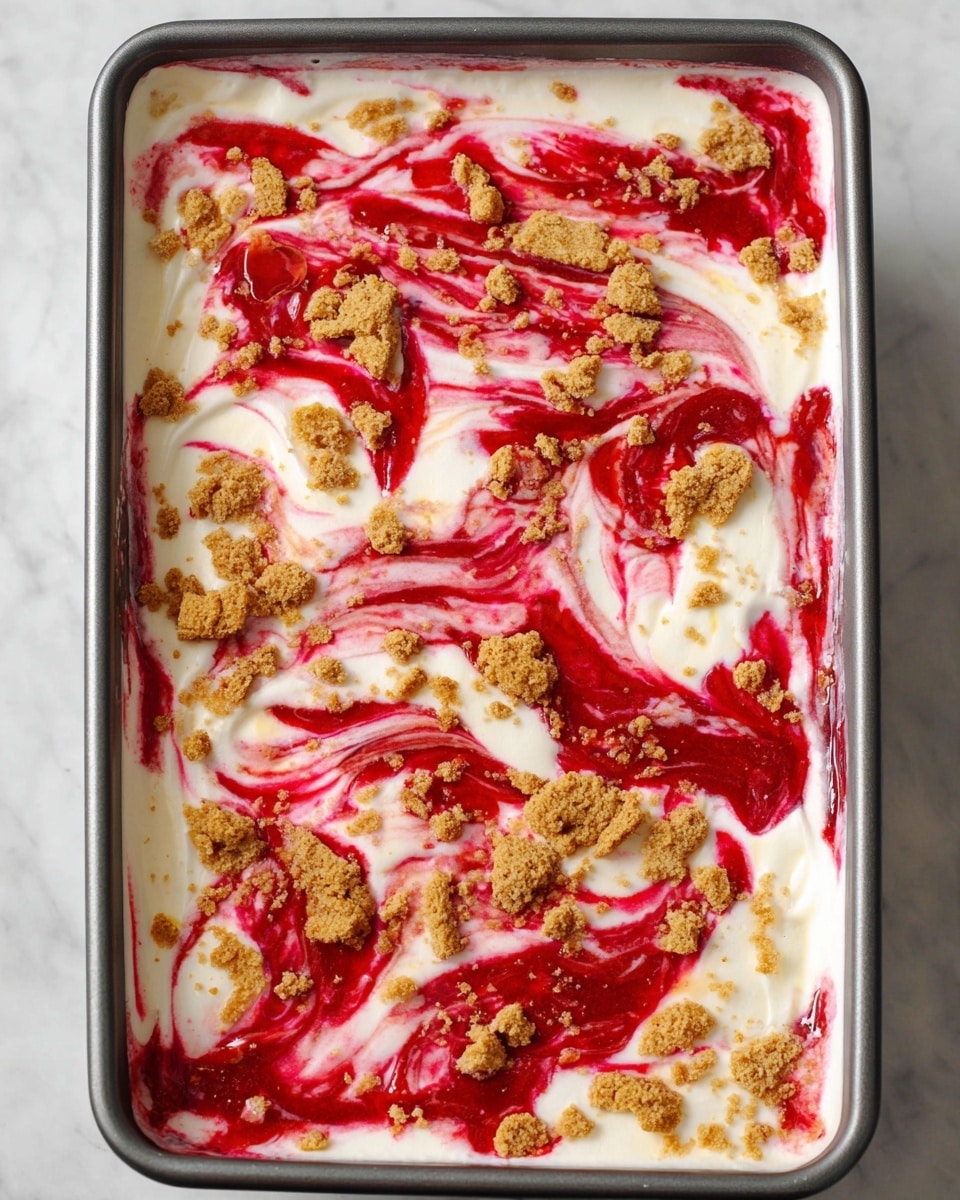 The image shows a rectangular baking pan filled with a dessert that has three visible layers. The base layer is creamy white, thick and smooth, with bright red swirls spread unevenly on the top, creating a marbled effect. Scattered on top are small, irregular crumbled pieces of light brown crunchy topping that contrast with the smooth cream and vibrant red sauce. The overall look is colorful and textured, with the red and white swirls blending together and the crunchy bits adding visual interest on the surface. The pan sits on a white marbled surface. photo taken with an iphone --ar 4:5 --v 7