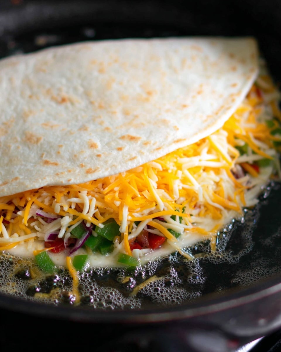 A soft white tortilla folded over a filling with visible layers: the bottom layer shows small pieces of green and red vegetables, possibly bell peppers and onions, followed by a generous layer of shredded cheddar and mozzarella cheese with yellow and white strands mixed together. The tortilla sits cooking in a pan with bubbling melted butter around the edges, giving a shiny and slightly crispy texture beginning to form on the tortilla. The close-up view highlights the textures of the fresh vegetables and the soft cheese inside. photo taken with an iphone --ar 4:5 --v 7