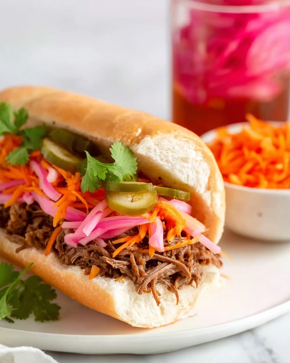 A white sandwich roll is filled with layers of shredded brown meat at the bottom, topped with thin slices of pink pickled onions and green pickle slices. Above these, there are bright orange shredded carrots and fresh green cilantro leaves that add color and texture. The sandwich is placed on a white plate with a slight view of a jar containing pink pickled onions and a small bowl of orange shredded carrots in the background, all set on a white marbled texture. Photo taken with an iphone --ar 4:5 --v 7