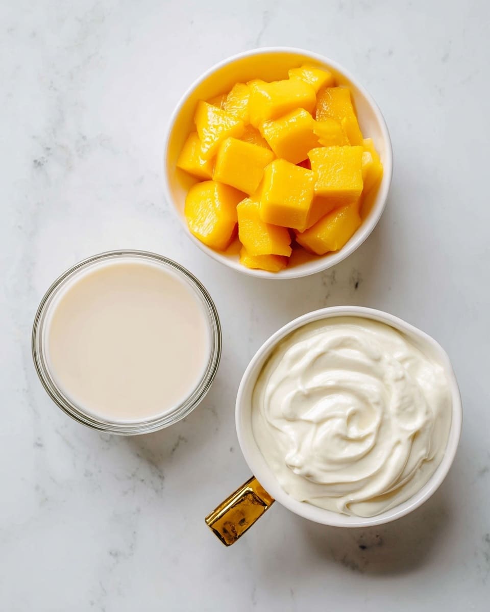 The image shows three small white containers placed on a white marbled surface. The first container at the top right holds bright yellow frozen mango chunks with a slightly frosty texture. The second container at the bottom right is a white bowl with a golden handle filled with thick, creamy white Greek yogurt that has smooth swirls on its surface. The third container at the bottom left is a clear glass bowl filled with light beige almond milk that looks smooth and liquid. The three containers are arranged close to each other with clear labels below each item. Photo taken with an iphone --ar 4:5 --v 7