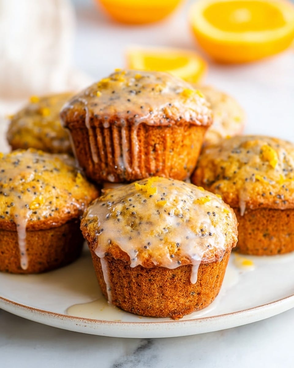 Five orange-colored muffins with black poppy seeds are placed on a white plate. Each muffin has a shiny glaze on top, with some drips running down the sides. The muffins have a rough, slightly crumbly texture with small orange zest bits visible. The plate sits on a white marbled surface, with slices of orange fruit visible blurred in the background. photo taken with an iphone --ar 4:5 --v 7