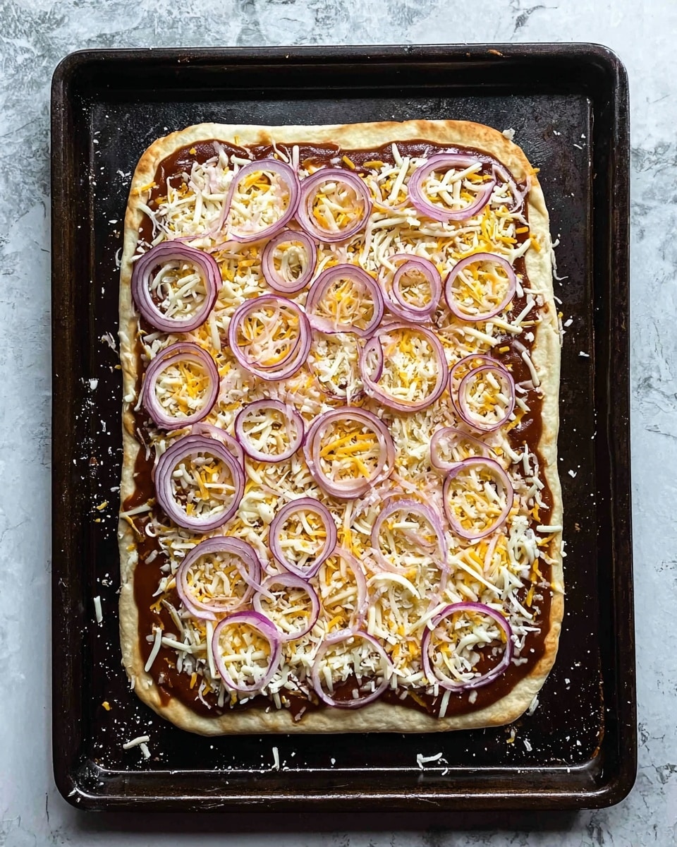 A rectangular flatbread pizza lies on a dark baking tray placed on a white marbled surface. The bottom layer is a light beige flatbread base evenly spread with a layer of rich, dark brown sauce. On top, there is a layer of shredded cheese combining white and yellow colors spread over the entire flatbread. Thin, curved slices of red onion are scattered across the cheese, adding a purplish tone and a fresh texture to the top. Some grated cheese and bits of onion have fallen around the edges on the tray. The overall look is fresh and ready to be cooked. photo taken with an iphone --ar 4:5 --v 7