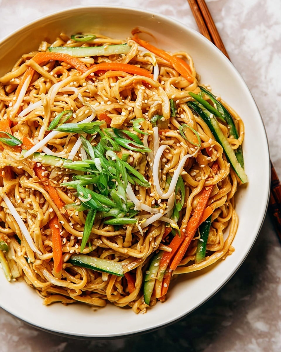 A white bowl filled with stir-fried noodles forms the main layer, showing a light golden-brown color with a slightly glossy surface. Mixed into the noodles are thin, bright orange carrot sticks and fresh green cucumber pieces, both cut into long strips and scattered evenly throughout. A layer of white bean sprouts adds a light, crisp texture atop the noodles. On top, thinly sliced green onions are sprinkled, giving a fresh green pop, and small toasted sesame seeds are scattered over everything, adding a bit of texture and a light tan color. The bowl sits on a white marbled surface with a wooden chopstick visible on the side. photo taken with an iphone --ar 4:5 --v 7