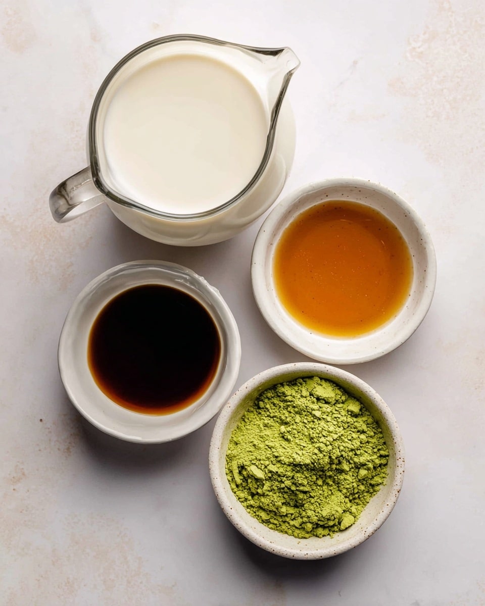 A clear glass pitcher filled with smooth, creamy white cashew milk sits near the top left on a white marbled surface. Below it, there are three small white ceramic bowls arranged in a slight arc: the top-right bowl contains rich amber maple syrup, the bottom-left bowl holds a dark golden vanilla liquid, and the bottom-center bowl is filled with bright green matcha powder, showing its fine, powdery texture. Each ingredient is clearly labeled in bold black letters next to its container. The overall setup is neat and clean with soft natural lighting. photo taken with an iphone --ar 4:5 --v 7