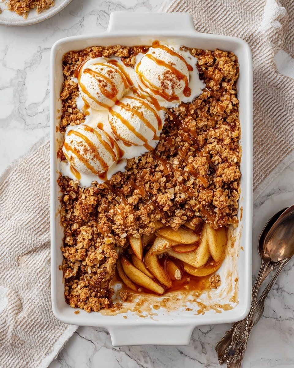 A rectangular white baking dish filled with apple crumble showing two main layers: the bottom layer of soft, sliced golden brown apples with a juicy look, and the top layer of a thick, crumbly oat and nut mixture with a toasted brown color. Three scoops of creamy white vanilla ice cream sit on the top left corner, each scoop drizzled with caramel sauce and lightly dusted with cinnamon powder. The crumble topping also has a light drizzle of caramel sauce spread unevenly. The dish rests on a white marbled surface with a light beige striped cloth and a vintage silver spoon nearby. Photo taken with an iphone --ar 4:5 --v 7