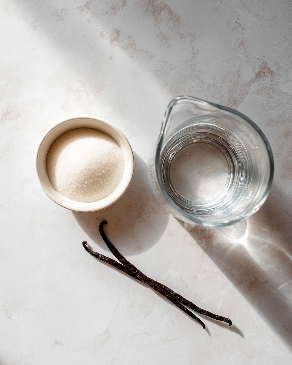 The image shows three ingredients on a white marbled surface: a small white bowl filled with fine white sugar on the left, a clear glass measuring cup with transparent water on the right, and a single dark brown vanilla bean pod laying diagonally at the bottom center. The lighting is soft and natural, creating a clean and simple look with shadows faintly visible around the items photo taken with an iphone --ar 4:5 --v 7