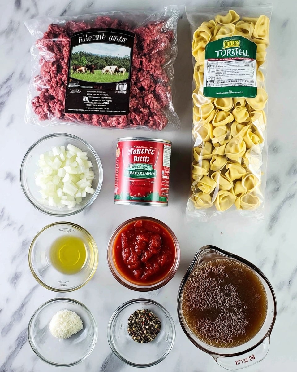 The image shows the ingredients for a meal arranged on a white marbled surface. There is a sealed plastic pack of ground sirloin beef with a dark label showing a green field and cows in the top left. To the right, a clear plastic bag of yellow three-cheese tortellini pasta with a green and white label is placed vertically. Below the tortellini, a red can of petite diced tomatoes with a white and green label sits on the right. Toward the bottom right, a glass measuring cup holds brown beef broth with some bubbles on the surface. In the middle near the bottom, a small glass bowl contains rich red tomato paste. Next to it on the left, a small metal measuring cup holds pale yellow oil. Three small glass bowls are placed on the bottom left: one has finely chopped white onion pieces, another has minced garlic, and the last contains mixed dry seasonings with black, white, and red flakes. The whole arrangement is neat and clearly shows each ingredient separately, set on the white marbled background photo taken with an iphone --ar 4:5 --v 7